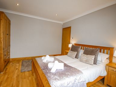 A bedroom with a wooden bed and wardrobe with pillows and towels on the bed at Family House in Weymouth
