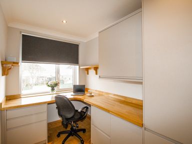 An office with a wooden desk a chair a laptop flowers in a vase and closed blinds at Family House in Weymouth