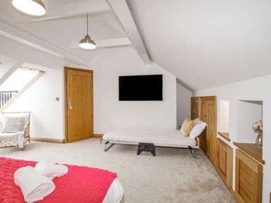 An attic bedroom with a bed and foldable bed against the wall and wooden doors at Family House in Weymouth