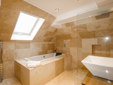 A bathroom with a built-in tub under a skylight window and a white basin on a wooden countertop at Family House in Weymouth