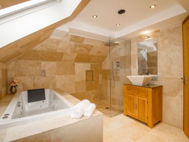 A bathroom with a built-in bathtub shower area wooden vanity and mirror at Family House in Weymouth