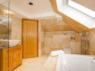 A bathroom with a wooden door a sink vanity a bathtub a toilet and a towel rack at Family House in Weymouth