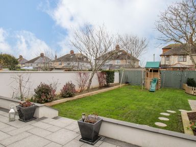 A garden with a grassy lawn a children's playset and potted plants at Family House in Weymouth