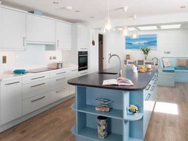 A kitchen with an island counter and seating area at The White House Polzeath