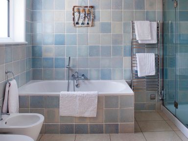A bathroom with a bathtub bidet towel rack and glass shower at The White House in Polzeath