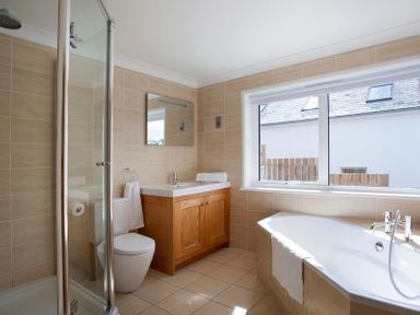 A bathroom with a bathtub towel sink mirror toilet and shower at The White House in Polzeath