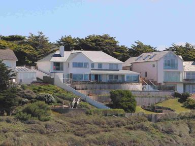 Houses on a hillside with stairs and trees in the background at The White House in Polzeath