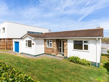 A single-story house with a tiled roof and stone entrance surrounded by a grassy yard at Zapadiah in Polzeath