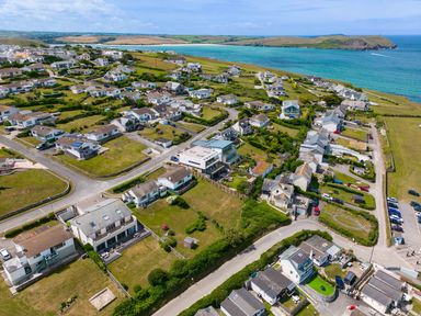 An aerial view of houses near a coastline with roads and green lawns at Zapadiah in Polzeath