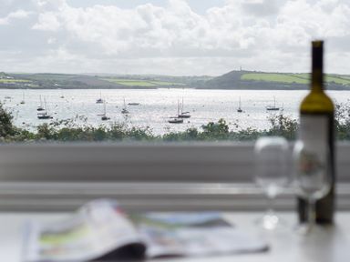 A window view of boats on water with hills in the background and a table with a wine bottle and glasses in the foreground at 4 The Terrace in Rock