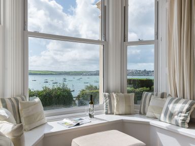 A window seat with cushions overlooking a bay with boats at 4 The Terrace in Rock