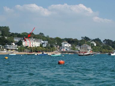 A coastal view of houses by the water with several boats anchored and a red buoy near the foreground at 4 The Terrace in Rock