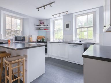 A kitchen with stools microwave oven and windows at 4 The Terrace in Rock