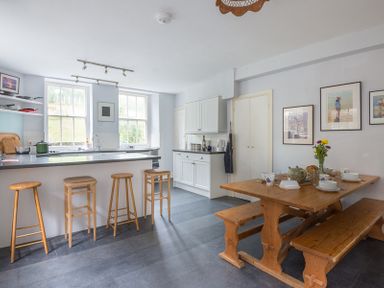 A kitchen with wooden stools at an island and a wooden dining table with benches at 4 The Terrace in Rock