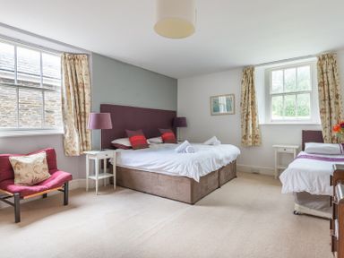A bedroom with a double bed and a single bed beside two windows with curtains at 4 The Terrace in Rock
