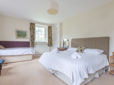 A bedroom with a double bed and a single bed near a window with curtains at 4 The Terrace in Rock