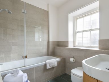 A bathroom with a bathtub shower combination a window a toilet and a sink at 4 The Terrace in Rock