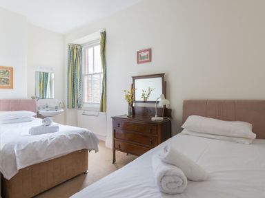 A bedroom with two beds a window a dresser with a mirror and a sink at 4 The Terrace in Rock