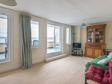 A living room with sofas a glass cabinet a small television and balcony doors at 4 The Terrace in Rock