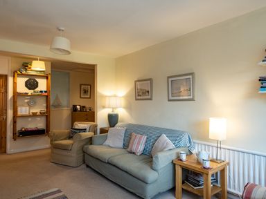 A living room with armchair couch side table lamps and bookshelf at Pencreek Rock
