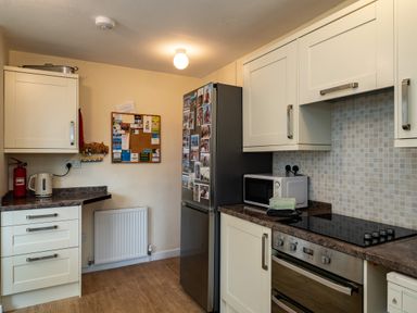 A kitchen with a fridge covered in photos a microwave stove and cabinets at Pencreek in Rock