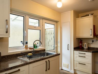 A kitchen with a sink drying rack soap bottles a kettle and a fire extinguisher at Pencreek Rock