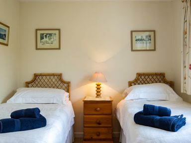 A bedroom with two single beds and a wooden nightstand with a lamp at Pencreek in Rock