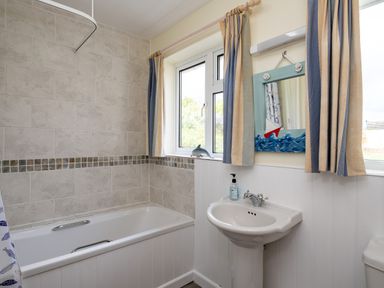 A bathroom with a bathtub sink mirror window and curtains at Pencreek in Rock