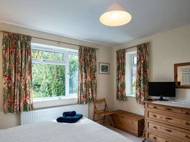 A bedroom with floral curtains wooden furniture and a television at Pencreek in Rock