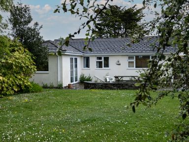 A single story house with a garden lawn and outdoor seating at Pencreek in Rock