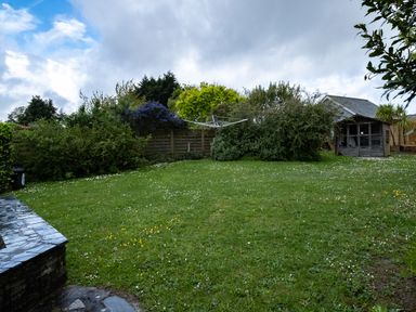 A garden with grass shrubs a wooden shed and a rotary clothesline at Pencreek in Rock