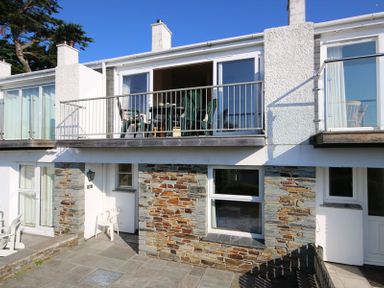 A two-story building with stone and white walls and a balcony with green chairs at Slipway 10 in Rock