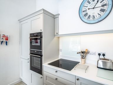 A kitchen corner with built in double oven electric stove kettle toaster and a large clock on the wall at Slipway 10 in Rock