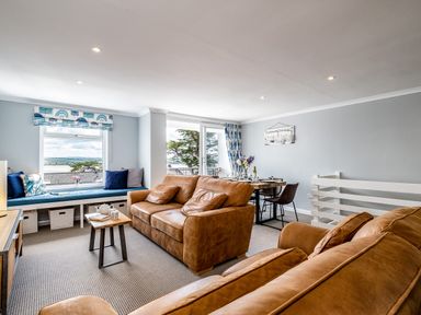 A living room with brown sofas a window seat and a dining table at Slipway 15 in Rock