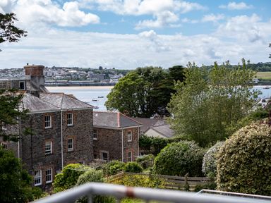 A view of a coastal town with stone buildings trees bushes and boats on the water at Slipway 15 in Rock