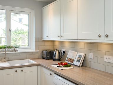 A kitchen counter with a sink toaster kettle cookbook and vegetables at Slipway 15 in Rock