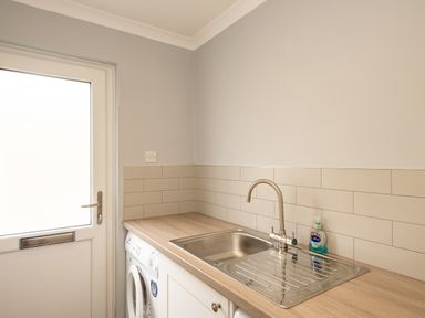 A kitchen with a sink, washing machine, and a door next to the counter at Slipway 15 in Rock