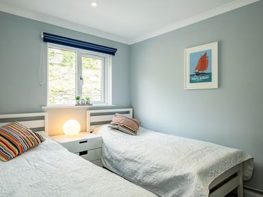 A bedroom with two single beds a window a nightstand with a lamp and a framed sailboat picture on the wall at Slipway 15 in Rock