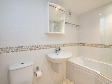 A bathroom with a toilet sink and bathtub with pebble tile border at Slipway 15 Rock