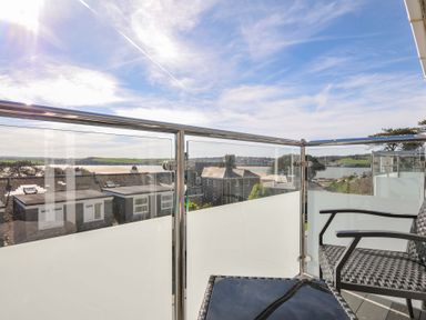 A balcony with chairs and a table overlooking water and buildings at Slipway 15 in Rock