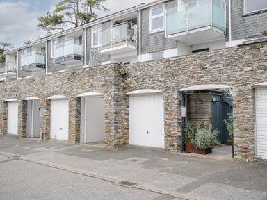 A row of garages with stone walls underneath apartments with balconies at Slipway 16 in Rock