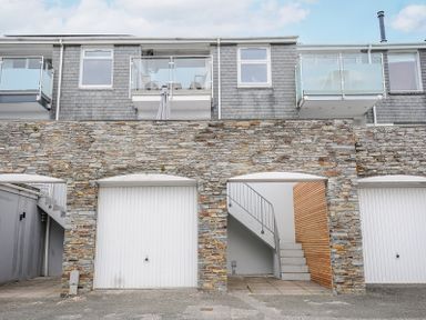 A view of the exterior showing stone walls with two white garage doors and an open stairway leading upstairs at Slipway 16 in Rock