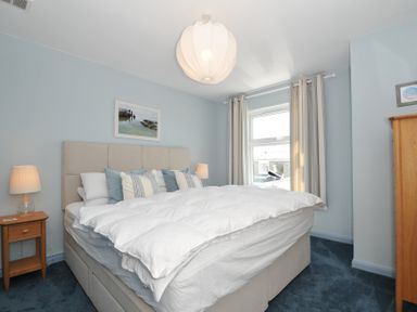 A bedroom with a bed with pillows and bedside tables with lamps at Slipway 16 in Rock