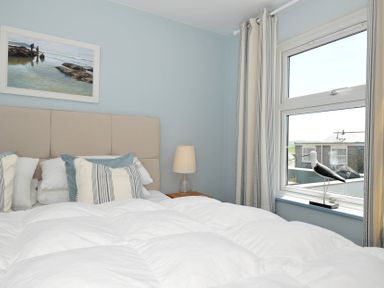 A bedroom with a bed pillows a bedside table lamp a window with curtains and a bird decoration at Slipway 16 in Rock