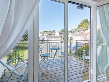 A balcony with a small blue table and two blue chairs viewed through glass doors at Slipway 19 in Rock