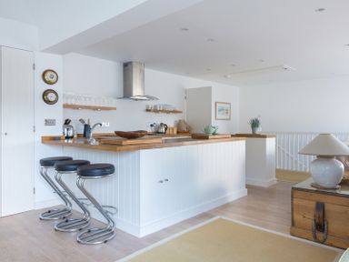 A kitchen with wooden countertops three bar stools and a lamp on a wooden chest at Slipway 19 in Rock
