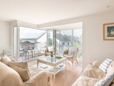 A living room with beige sofas and a white coffee table next to a balcony with plastic chairs at Slipway 19 in Rock