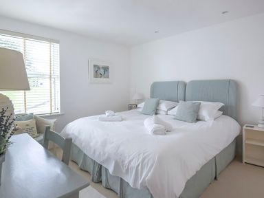 A bedroom with a double bed pillows lamps and a window with blinds at Slipway 19 in Rock