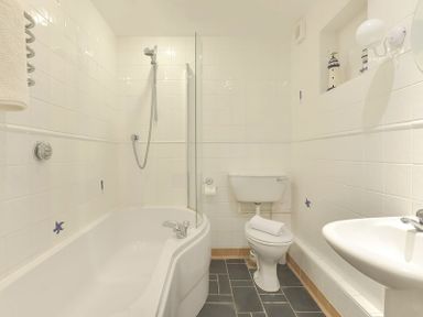 A bathroom with a bathtub shower combination a toilet and a sink at Slipway 19 in Rock