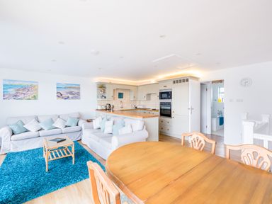 A living room with two sofas and blue rug next to a kitchen with wooden countertops and dining table at Slipway 21 in Rock